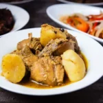 Jamaican Brown Stew Chicken with Coconut Dumplings, Callaloo, and Fried Plantains