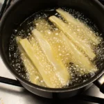 Fried cassava sticks frying in a pan