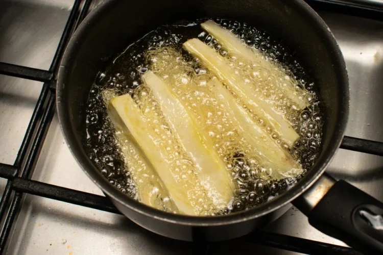 Fried cassava sticks frying in a pan